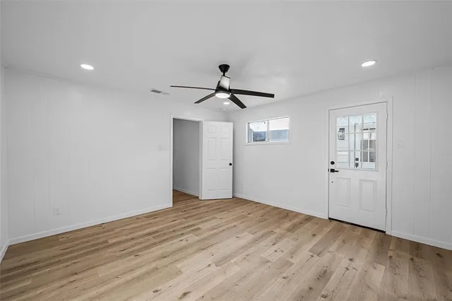 a view of empty room with wooden floor and ceiling fan