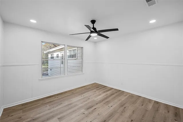 a view of empty room with wooden floor and fan