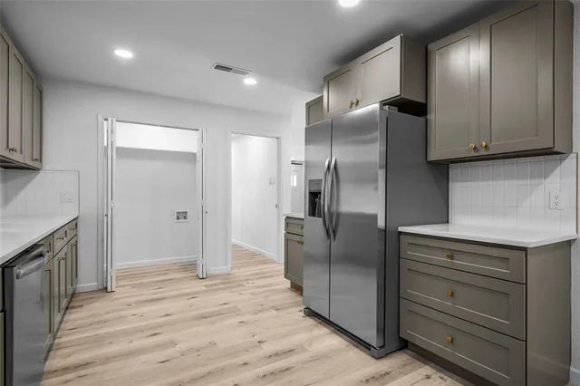 a kitchen with stainless steel appliances cabinets and wooden floor