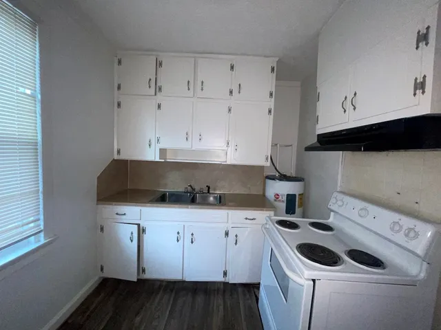 a kitchen with granite countertop a sink a stove and cabinets