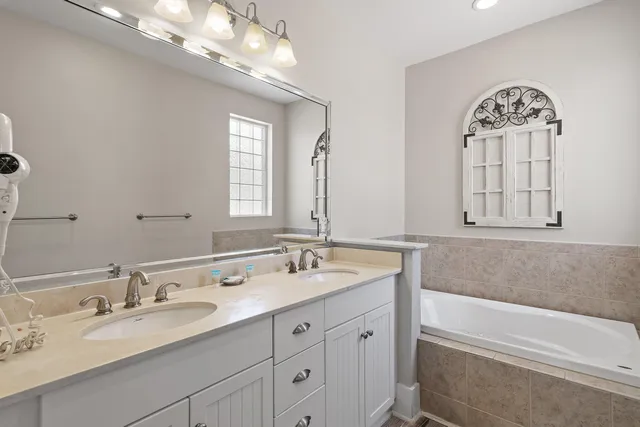 a bathroom with a granite countertop bathtub a double vanity sink and a mirror