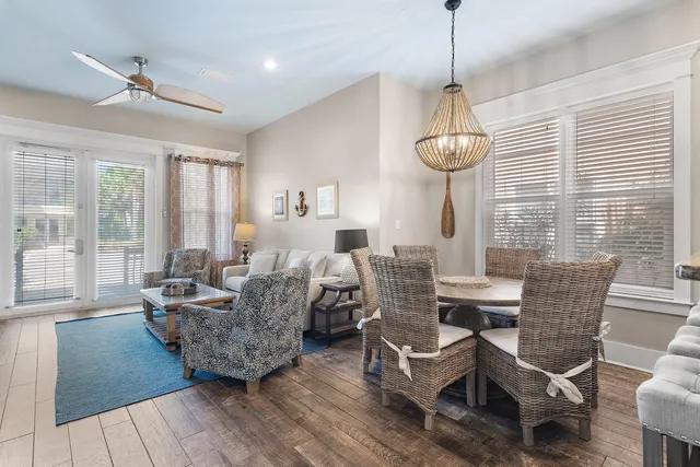 a living room with couches a dining table and a chandelier with wooden floor