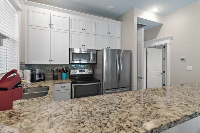 a kitchen with granite countertop a refrigerator and a stove top oven