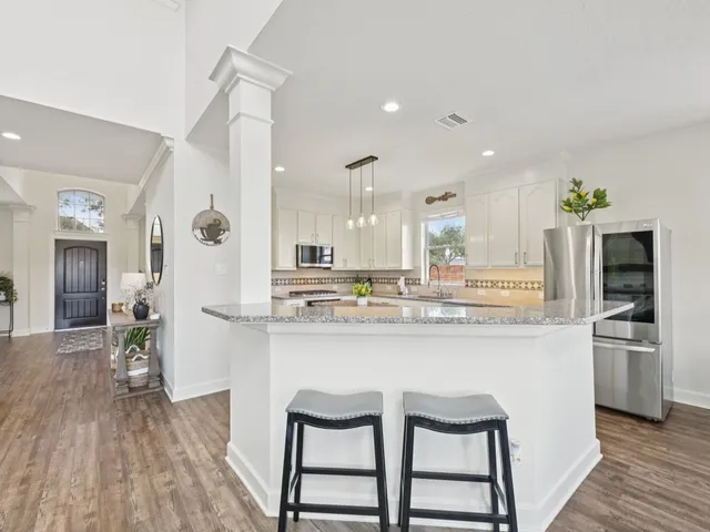 a kitchen with granite countertop a stove top oven a sink dishwasher and a fireplace with wooden floor