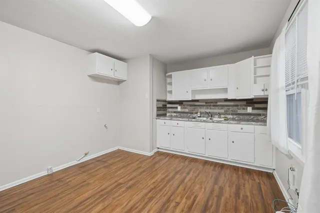 a room with granite countertop white cabinets and wooden floor