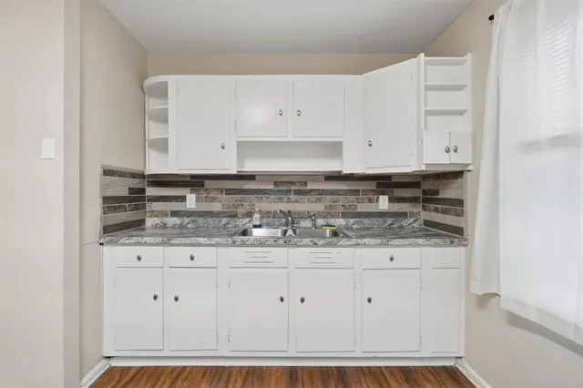 a view of kitchen with granite countertop white cabinets