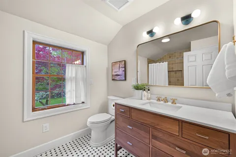 a bathroom with a toilet a sink a large mirror and shower
