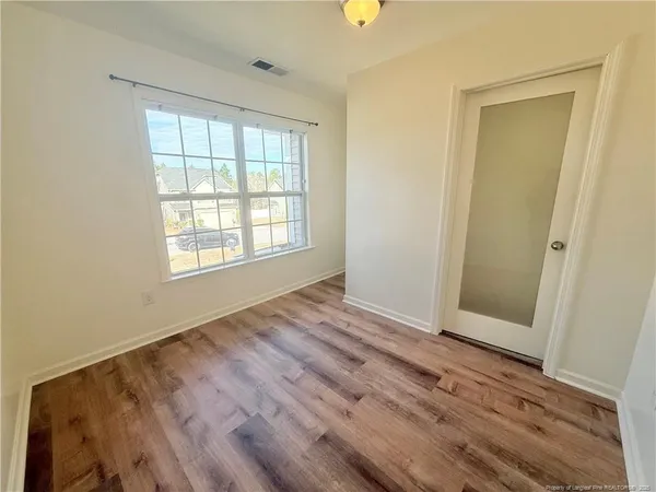 an empty room with wooden floor and windows