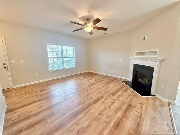 a view of empty room with wooden floor and fan