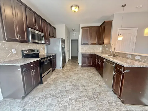 a large kitchen with stainless steel appliances granite countertop a sink stove and refrigerator