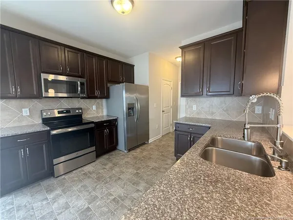 a kitchen with stainless steel appliances granite countertop a refrigerator a stove a sink and a microwave