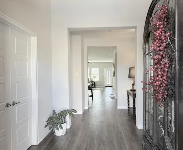 a hallway with wooden floor chandelier and livingroom view
