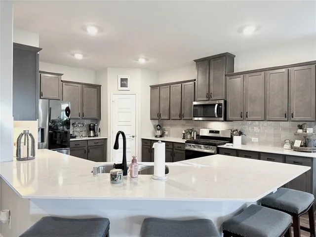 a kitchen with stainless steel appliances a sink a microwave a refrigerator and cabinets