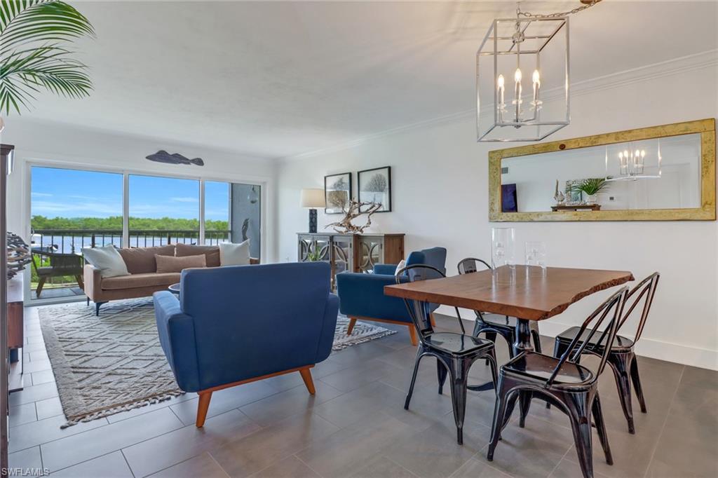 Dining space featuring a water view, tile patterned flooring, crown molding, and a notable chandelier
