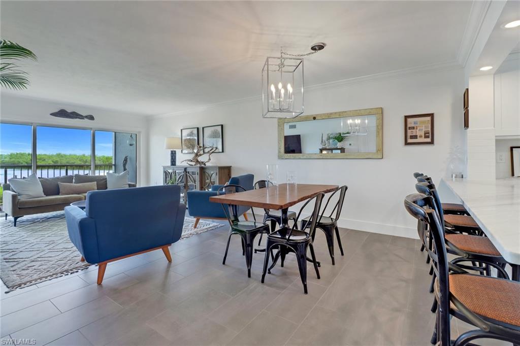 Dining room featuring ornamental molding, light tile patterned floors, and an inviting chandelier