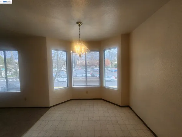 an empty room with window and chandelier fan
