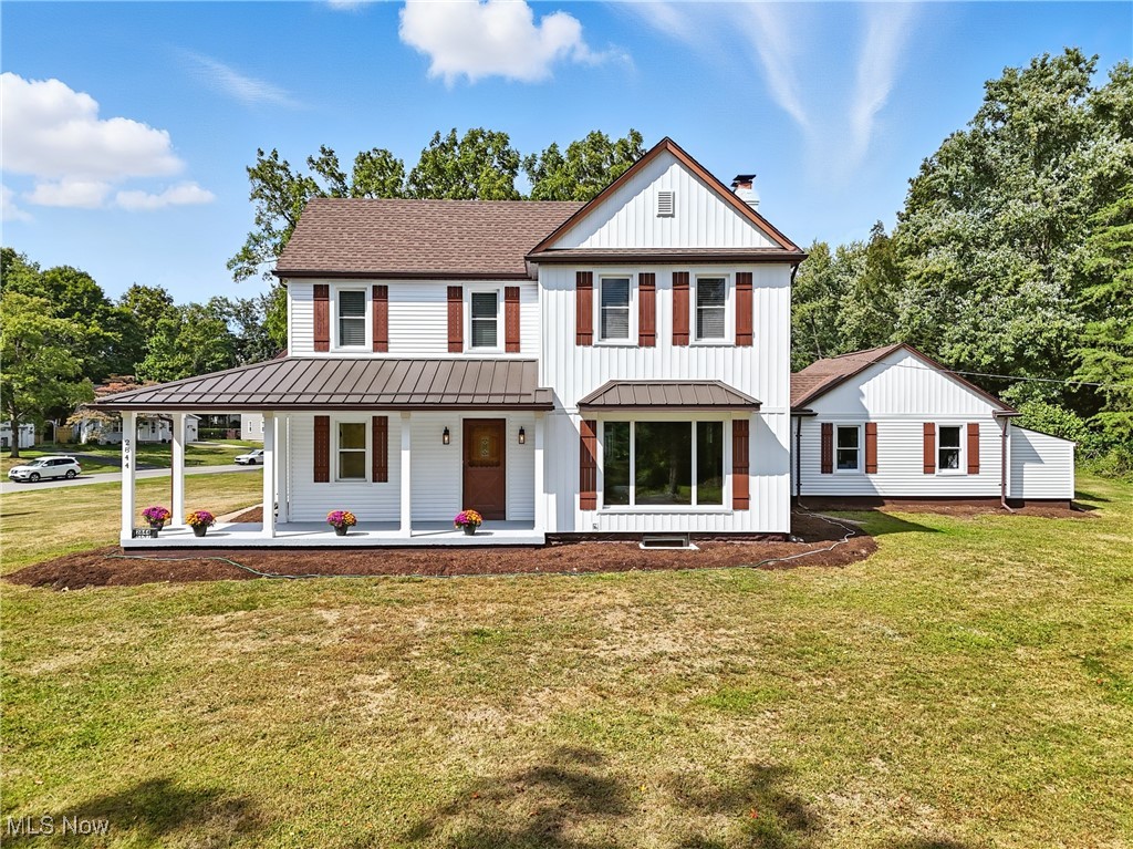 Modern farmhouse featuring covered porch, a front yard, board and batten siding, a chimney, and roof with shingles