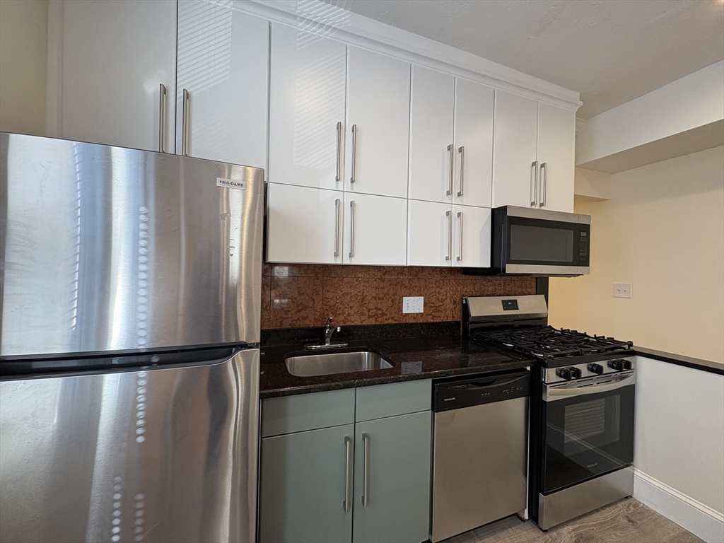 73 Thatcher Street, Unit 301 Brookline, MA 02446 - Photo 2 of 15 a kitchen with granite countertop a refrigerator stove and microwave