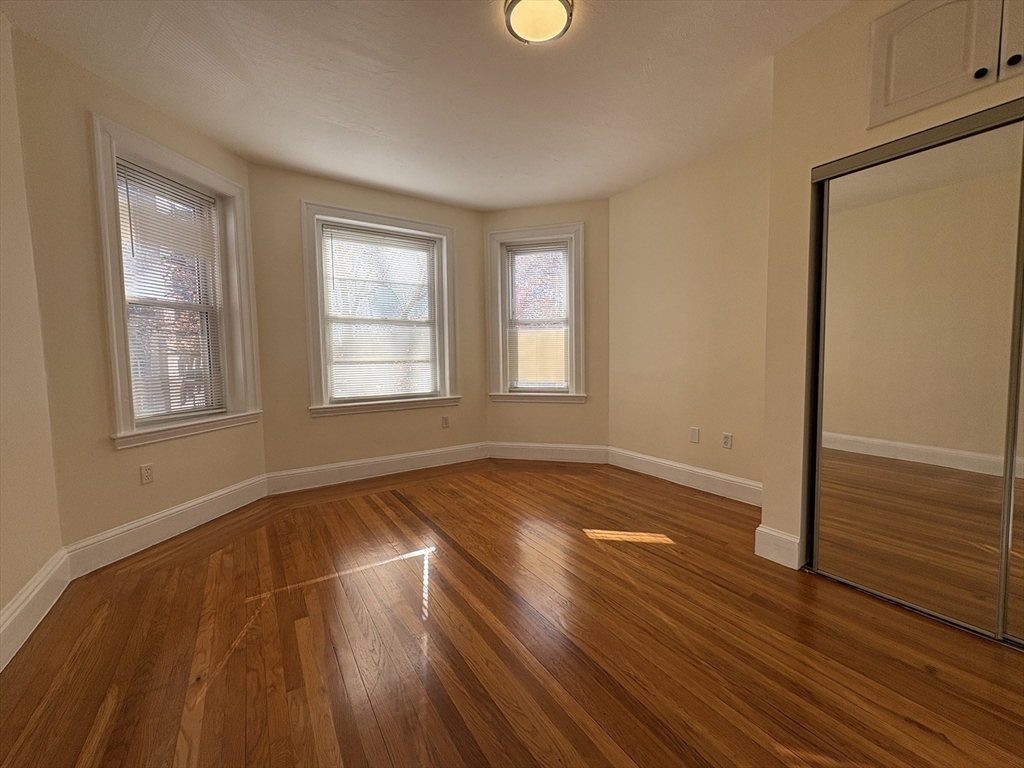 73 Thatcher Street, Unit 301 Brookline, MA 02446 - Photo 7 of 15 an empty room with wooden floor and windows