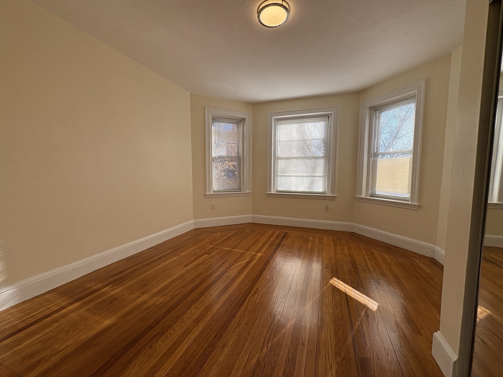 73 Thatcher Street, Unit 301 Brookline, MA 02446 - Photo 8 of 15 an empty room with wooden floor and windows