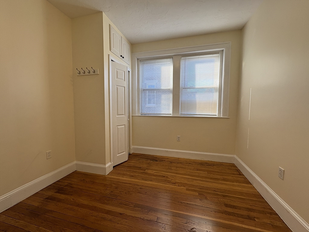 73 Thatcher Street, Unit 301 Brookline, MA 02446 - Photo 9 of 15 a view of an empty room with wooden floor and a window