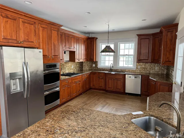 a kitchen with granite countertop a sink stainless steel appliances and window