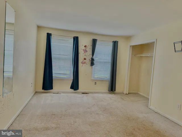 a view of an empty room with closet and wooden door