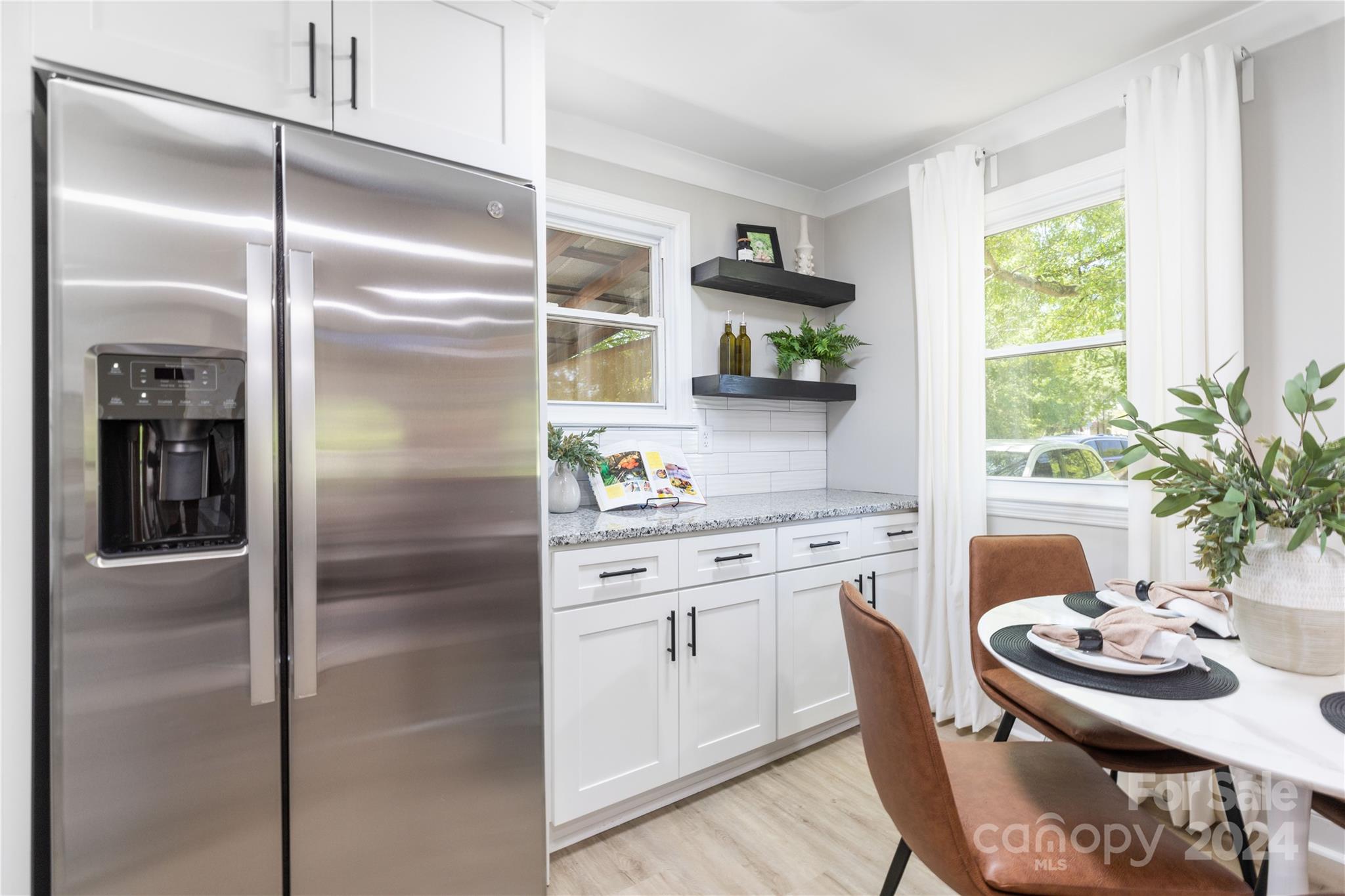 a kitchen with stainless steel appliances kitchen island granite countertop a refrigerator a sink a stove and white cabinets