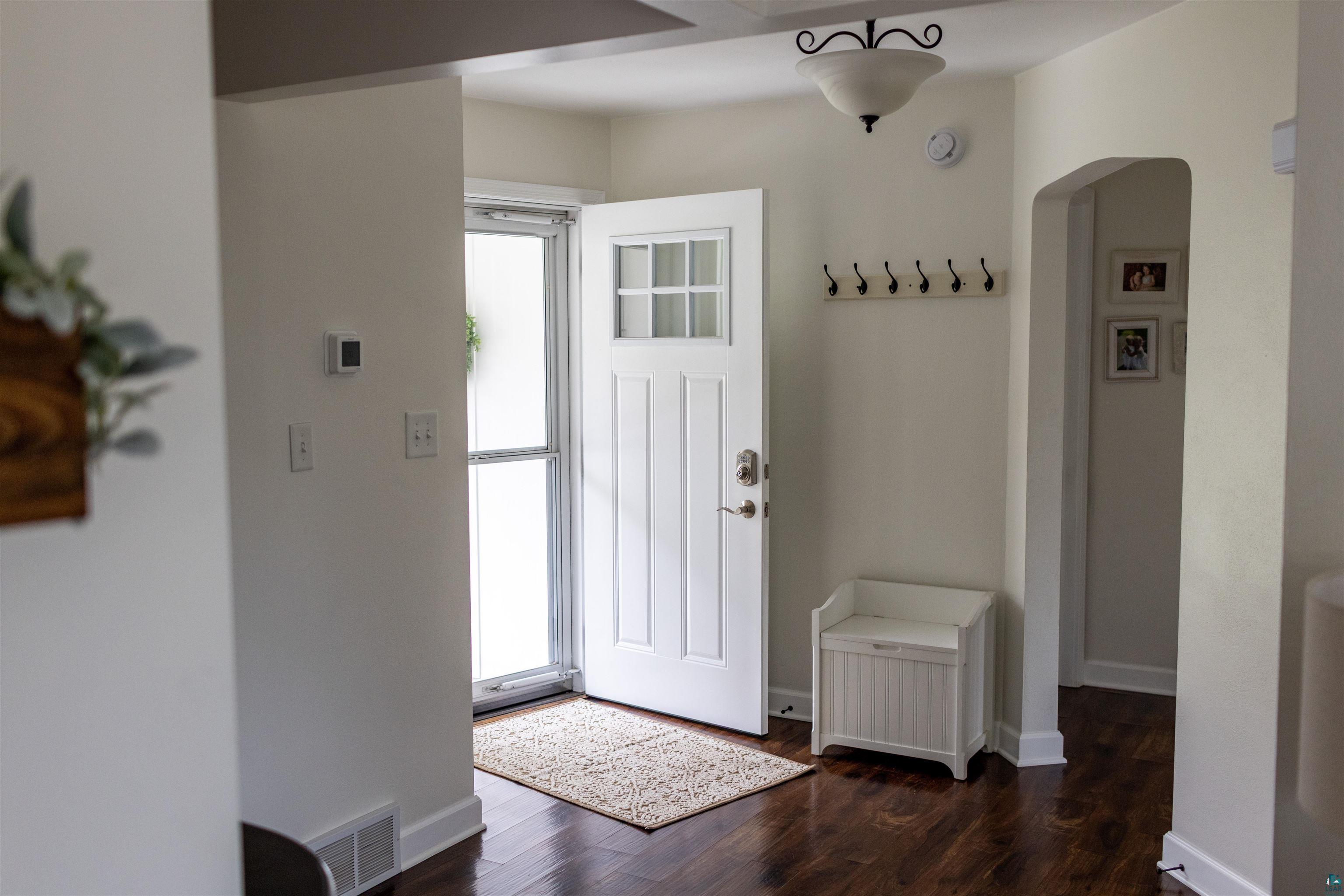 3704 Greysolon Road Duluth, MN 55804 - Photo 13 of 51 Entryway featuring a white paneled door with glass inserts, wood-finish flooring, white baseboards, and a recessed archway
