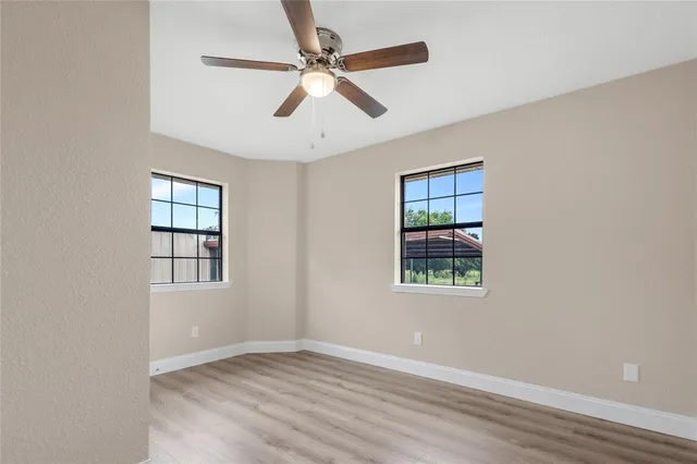 an empty room with windows and fan