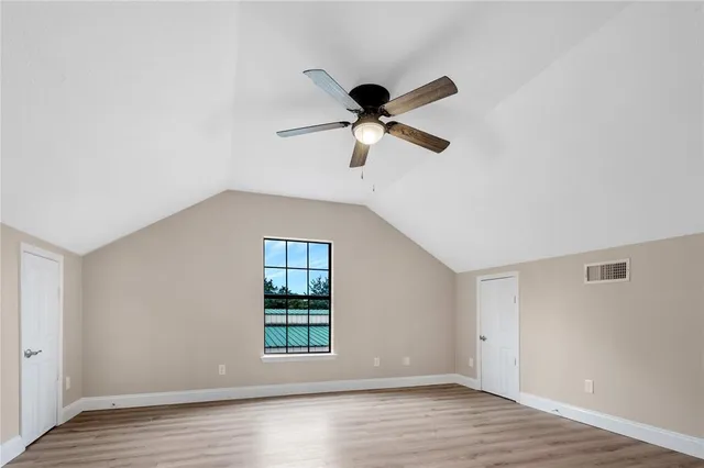 an empty room with wooden floor fan and windows