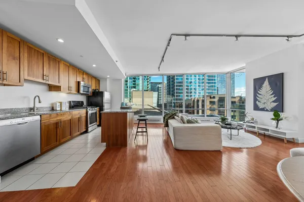 a living room with kitchen island granite countertop wooden floor a couch and a kitchen view