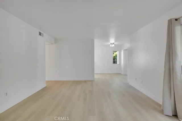 a view of an empty room with window and wooden floor
