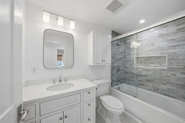 a spacious bedroom with a bed a dresser and windows