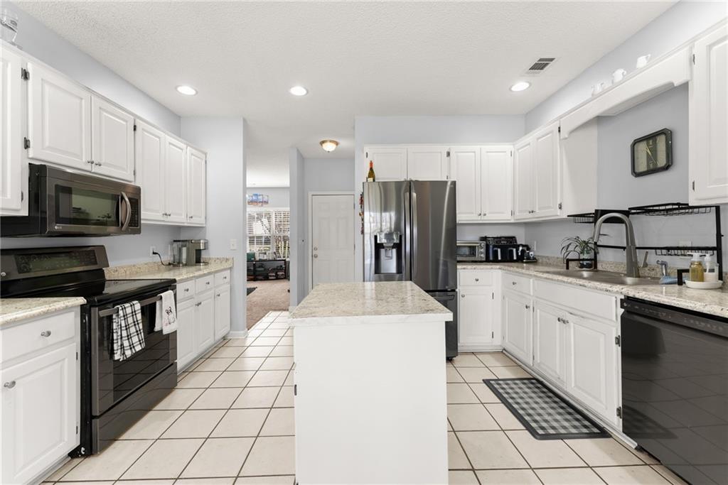 716 Michael Drive Winder, GA 30680 - Photo 13 of 46 a kitchen with stainless steel appliances a refrigerator sink stove microwave and cabinets
