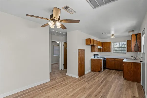a view of a kitchen with a refrigerator a ceiling fan and wooden floor
