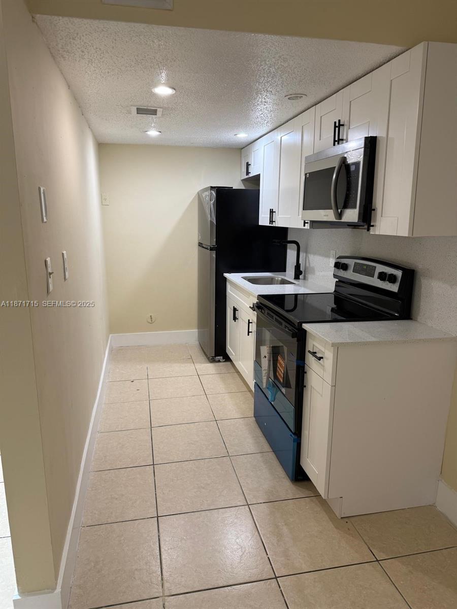 2377 West 66th Place, Unit 204 Hialeah, FL 33016 - Photo 11 of 17 a kitchen with stainless steel appliances a stove a sink a microwave a counter top space and cabinets