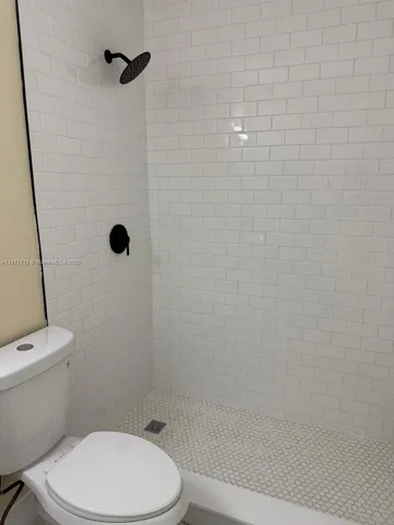 a white toilet sitting next to a shower
