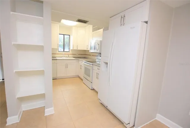 a kitchen with granite countertop white cabinets and white appliances