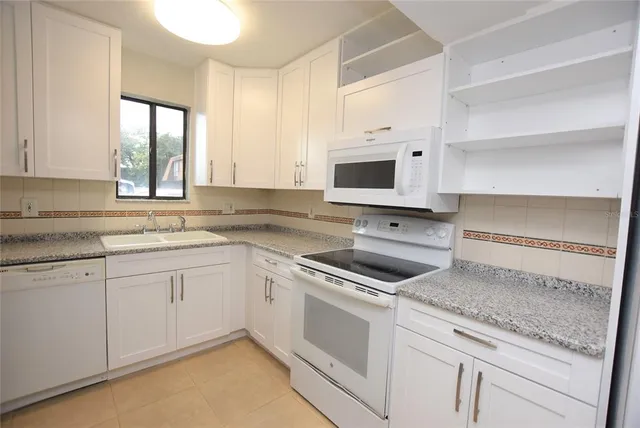 a kitchen with granite countertop white cabinets and white appliances