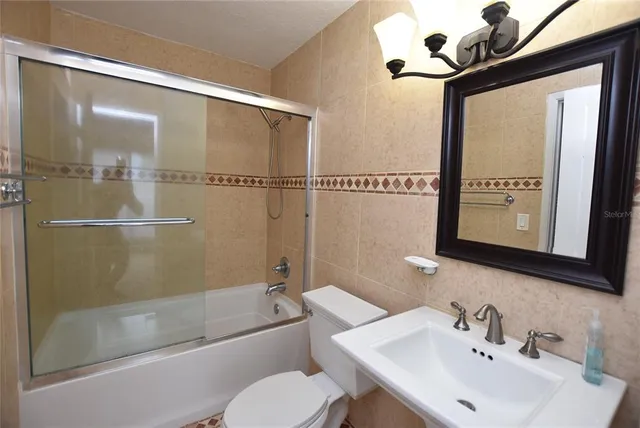 a bathroom with a sink mirror bathtub and toilet