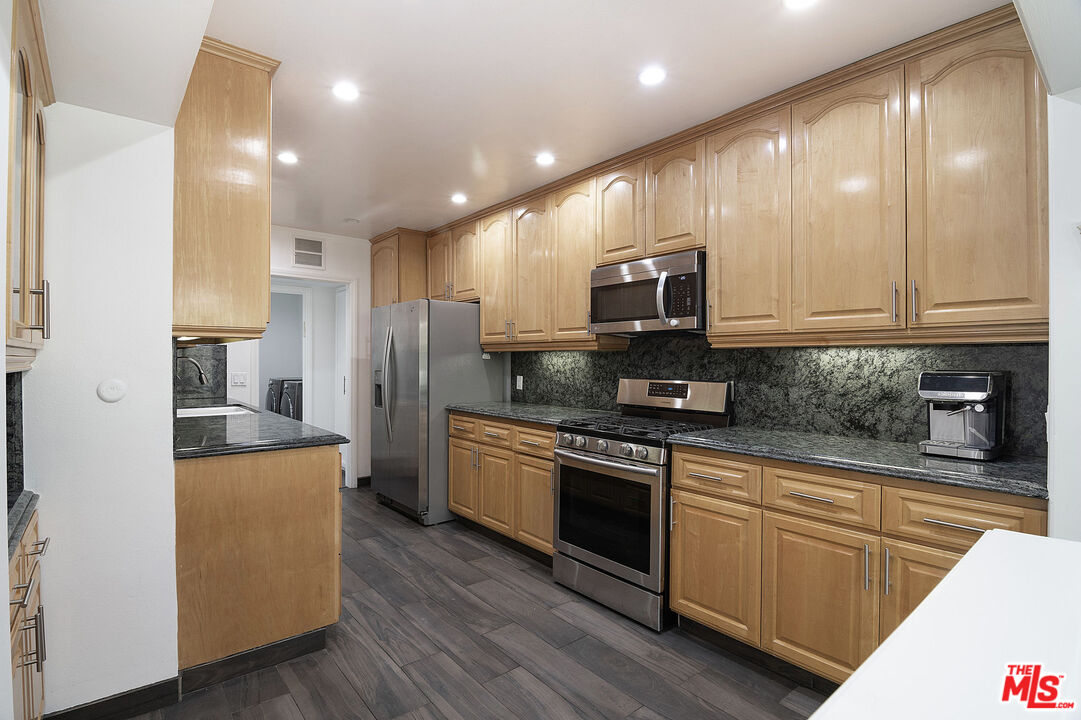 853 Le Doux Road, Unit 201 Los Angeles, CA 90035 - Photo 13 of 36 a kitchen with stainless steel appliances granite countertop wooden cabinets a refrigerator a stove a sink and a microwave
