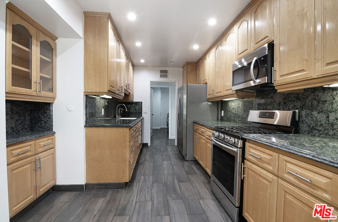 853 Le Doux Road, Unit 201 Los Angeles, CA 90035 - Photo 14 of 36 a kitchen with stainless steel appliances granite countertop wooden cabinets a refrigerator a stove a sink and a microwave