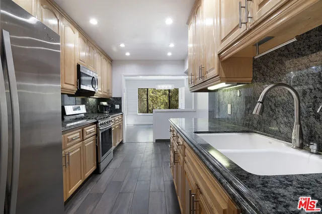 a kitchen with stainless steel appliances granite countertop a sink a stove and a refrigerator