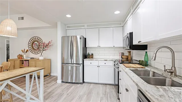 a kitchen with a refrigerator sink and white cabinets