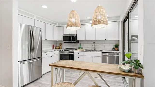 a kitchen with stainless steel appliances kitchen island granite countertop a refrigerator a stove a sink dishwasher a oven with a dining table and chairs