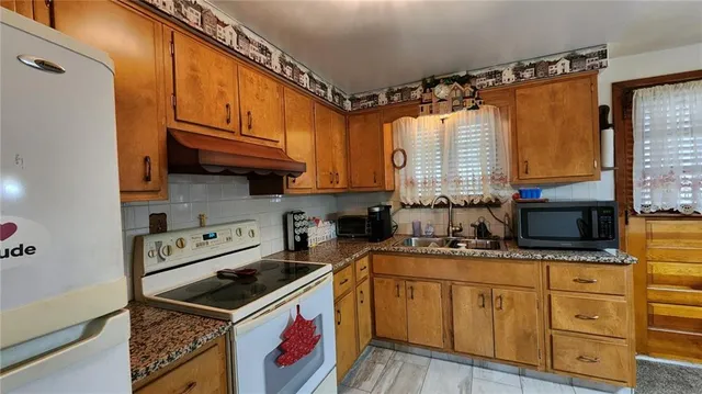 a kitchen with stainless steel appliances granite countertop a stove a sink and a refrigerator