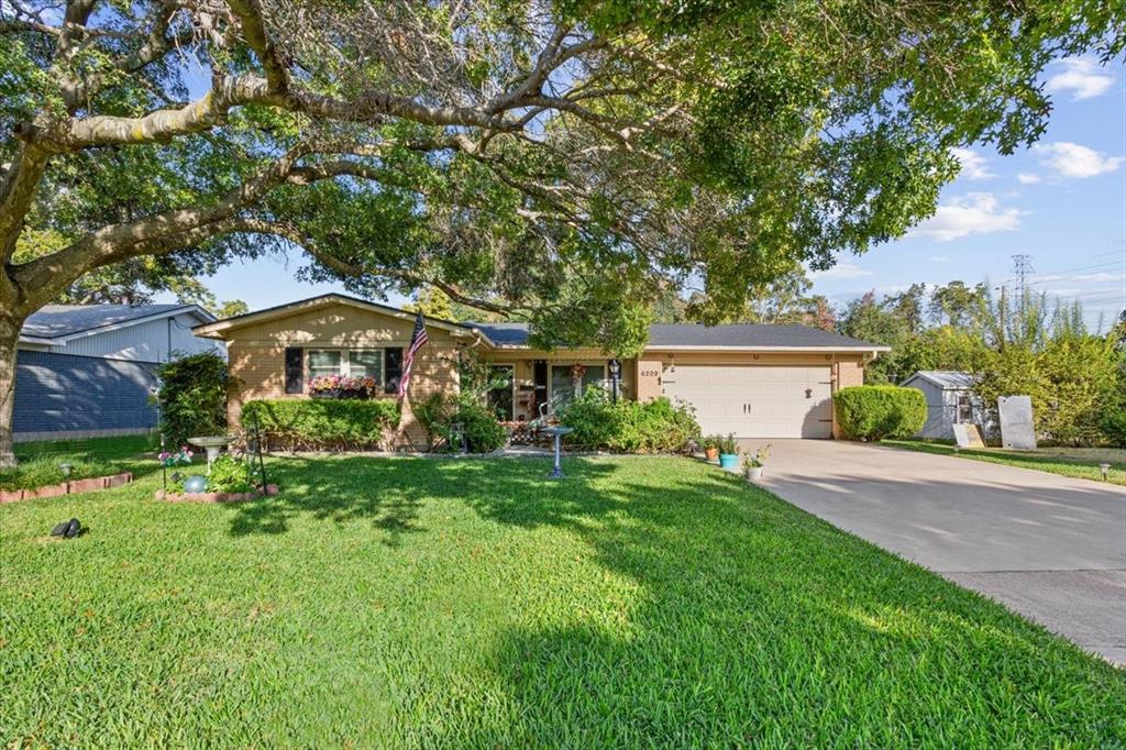 Single story home with concrete driveway, a front yard, an attached garage, and brick siding