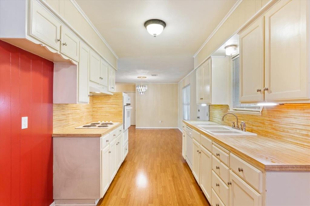 6209 May Drive Waco, TX 76710 - Photo 12 of 30 Kitchen with light countertops, crown molding, tasteful backsplash, light wood-style flooring, and white cabinetry