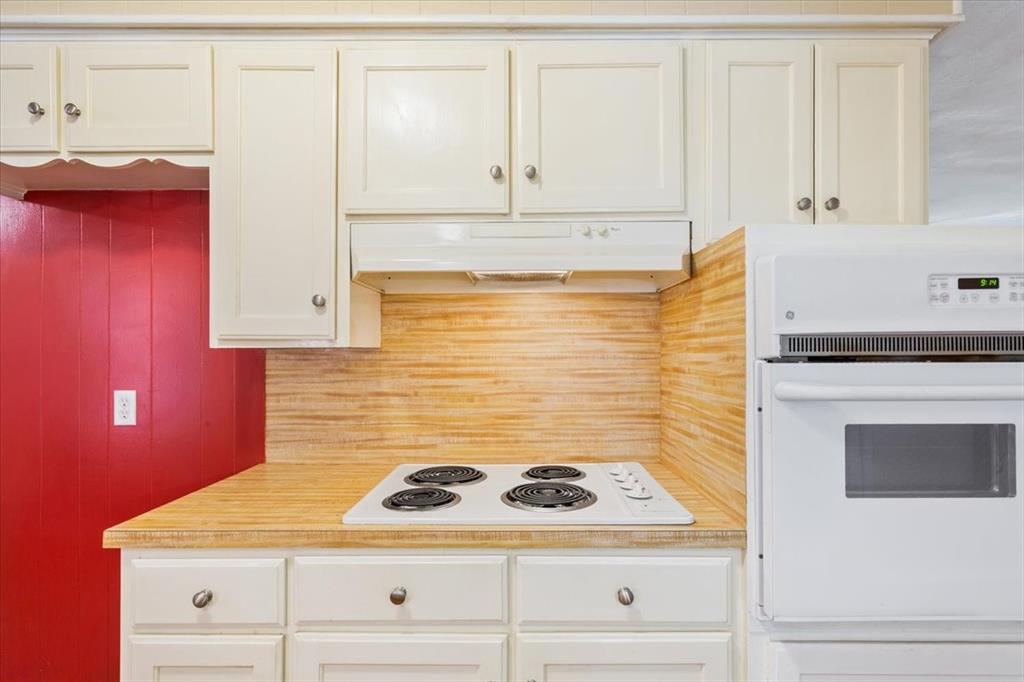 6209 May Drive Waco, TX 76710 - Photo 13 of 30 Kitchen featuring light countertops, white appliances, under cabinet range hood, and white cabinets